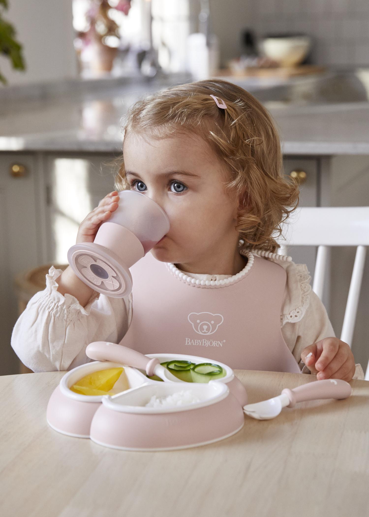 Dinnerware set in powder pink with baby plates, cup and cutlery and a bib with spill pocket - BabyBjörn